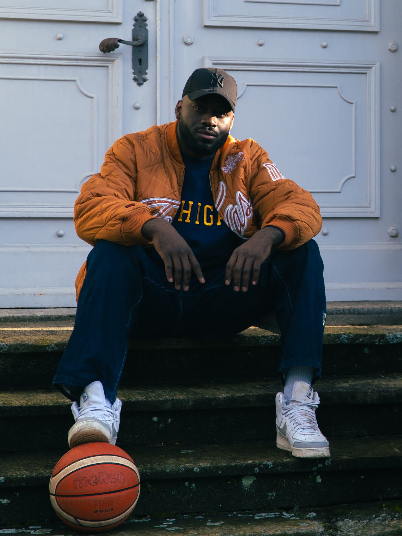 Homme assis sur des marches, bomber vintage orange